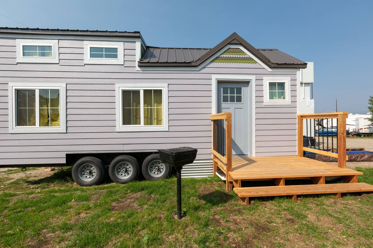 Une maison mobile dotée d’un toit plat, d’un porche à l’avant et d’une porte coulissante.