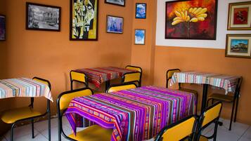 Un comedor con mesas y sillas, decorado con manteles coloridos y cuadros en la pared.