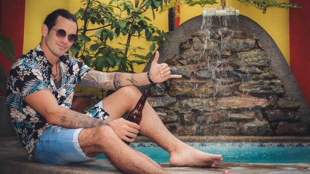A person sitting by a pool with a stone waterfall feature in the background. - Dreamkapture Hostel (Guayaquil)