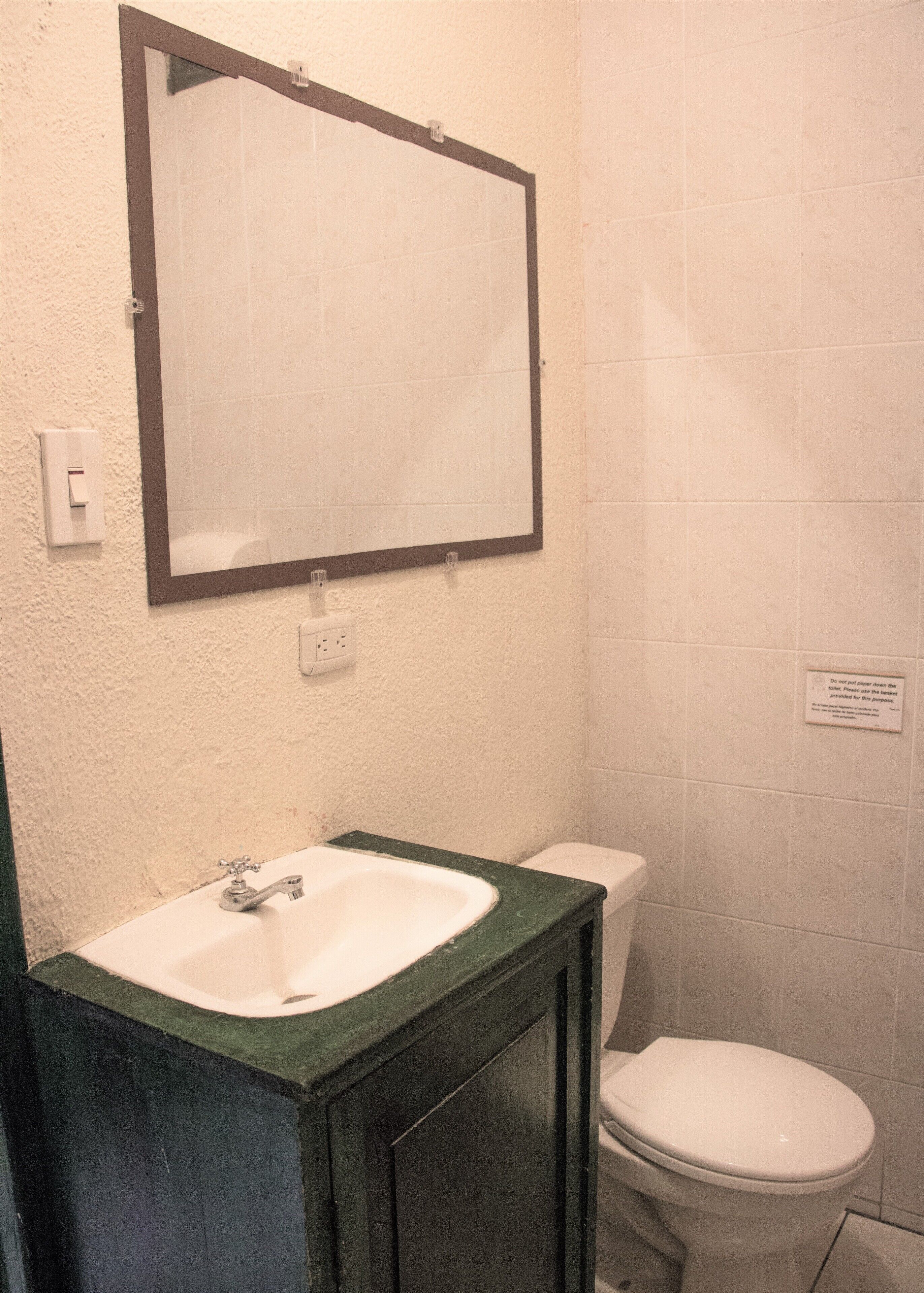 A bathroom with a white sink, a mirror, and a toilet.