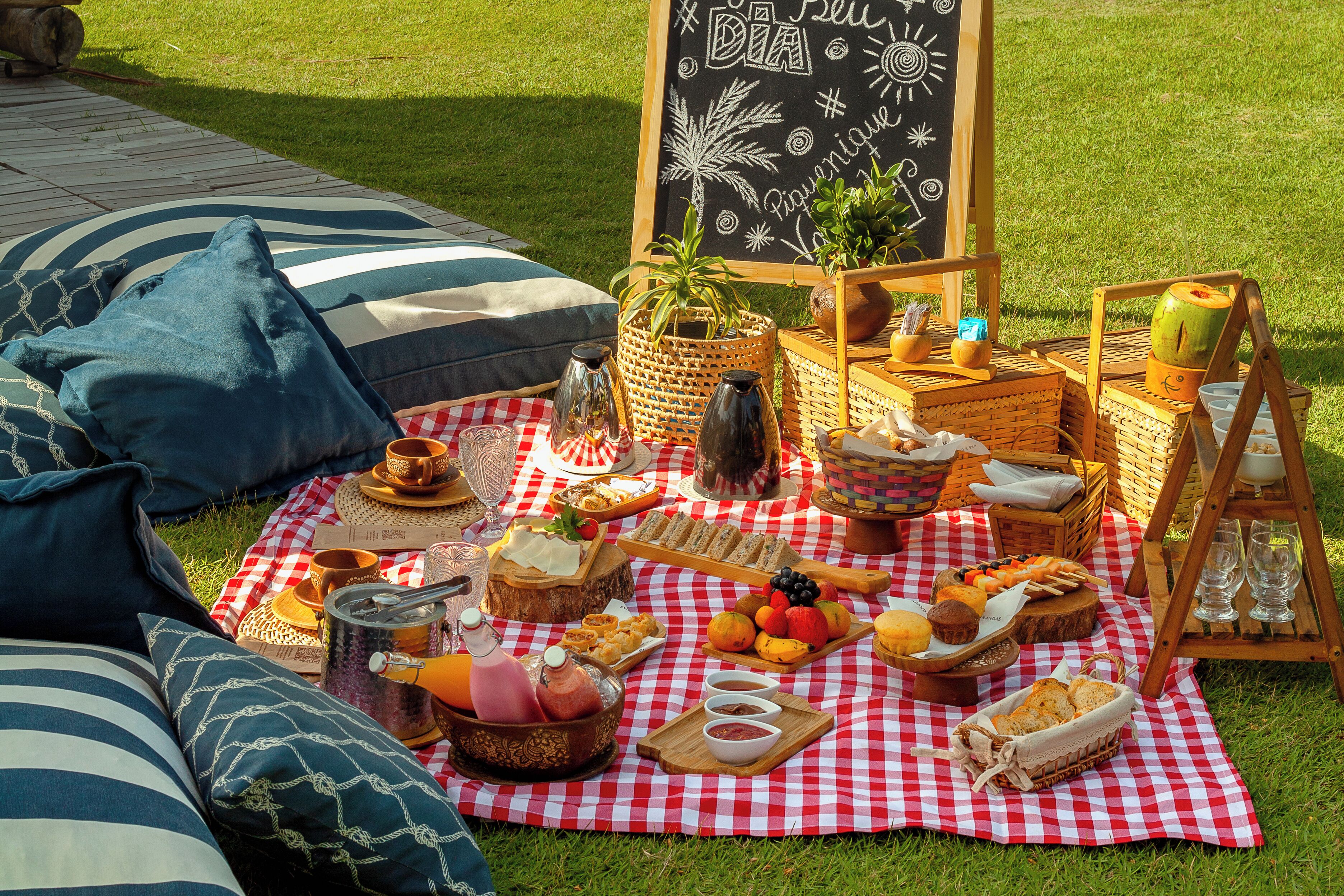 Een picknick op een geruit kleed met eten, drinken en een schoolbord.