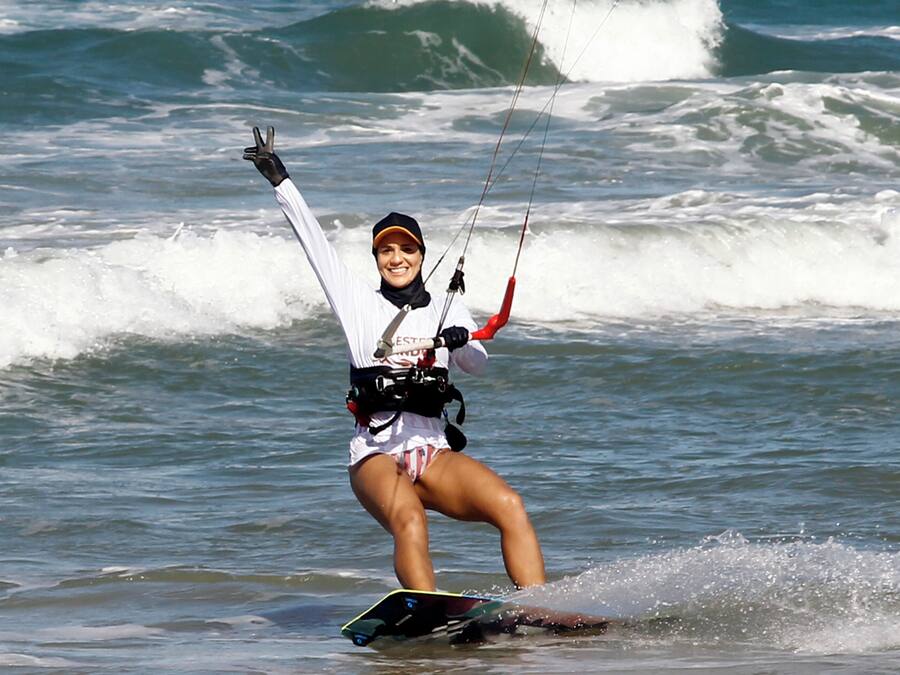 Uma pessoa praticando windsurf em uma prancha no oceano.