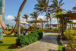 A paved pathway leading to a pool area with palm trees and outdoor seating.