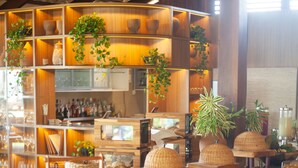 Ein Restaurantinneres mit Holzböden, Topfpflanzen und verschiedenen Tischgestaltungen.