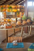 Un interior de restaurante con estanterías de madera, plantas en macetas y diferentes tipos de mesas dispuestas.