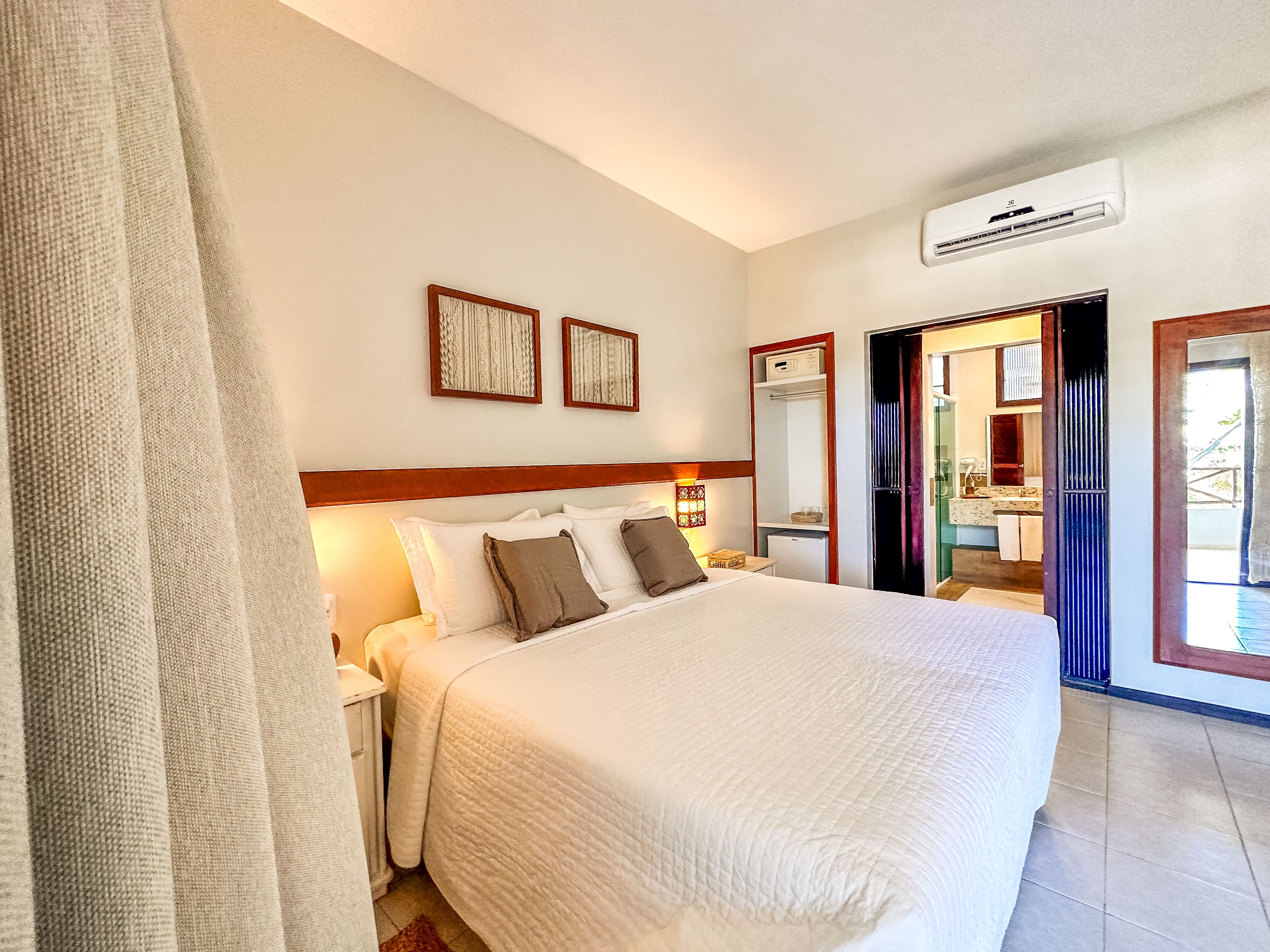 Habitación de hotel con una cama grande, una mesita de noche, un espejo y un equipo de aire acondicionado.