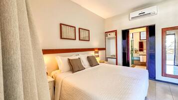 Habitación de hotel con una cama grande, una mesita de noche, un espejo y un equipo de aire acondicionado.