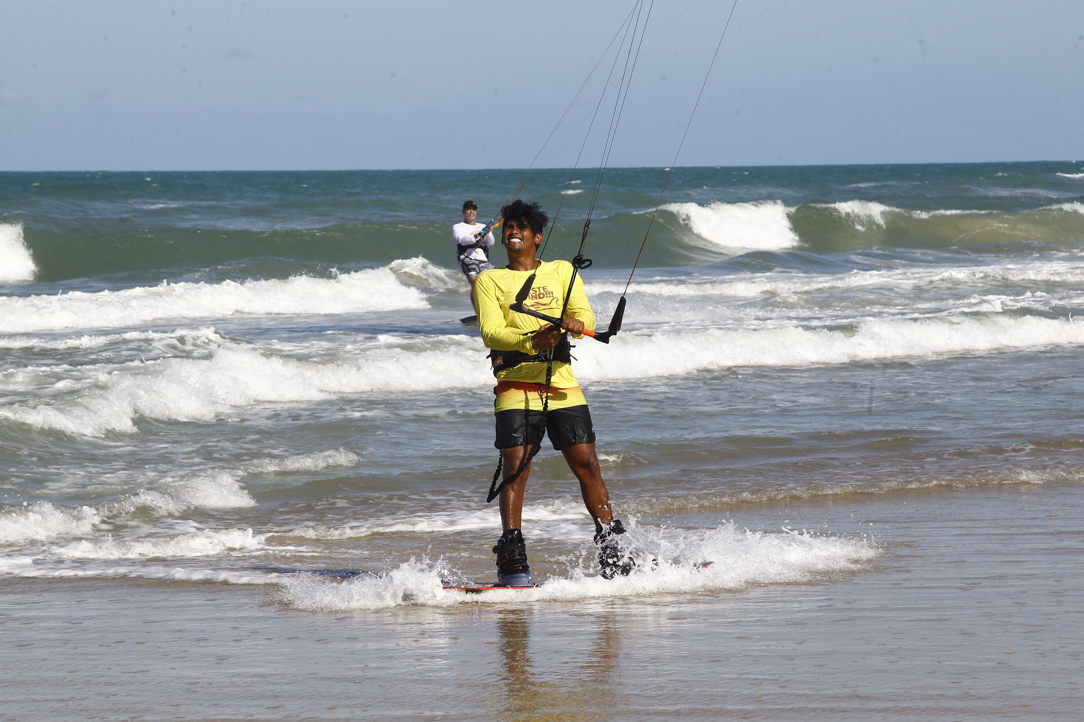 A person windsurfing on a beach with waves.
