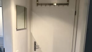 Eine weiße, geschlossene Tür mit einem Metallgriff und einem kleinen Spiegel darüber.