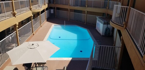 Une piscine extérieure entourée de balcons dotés de garde-corps.