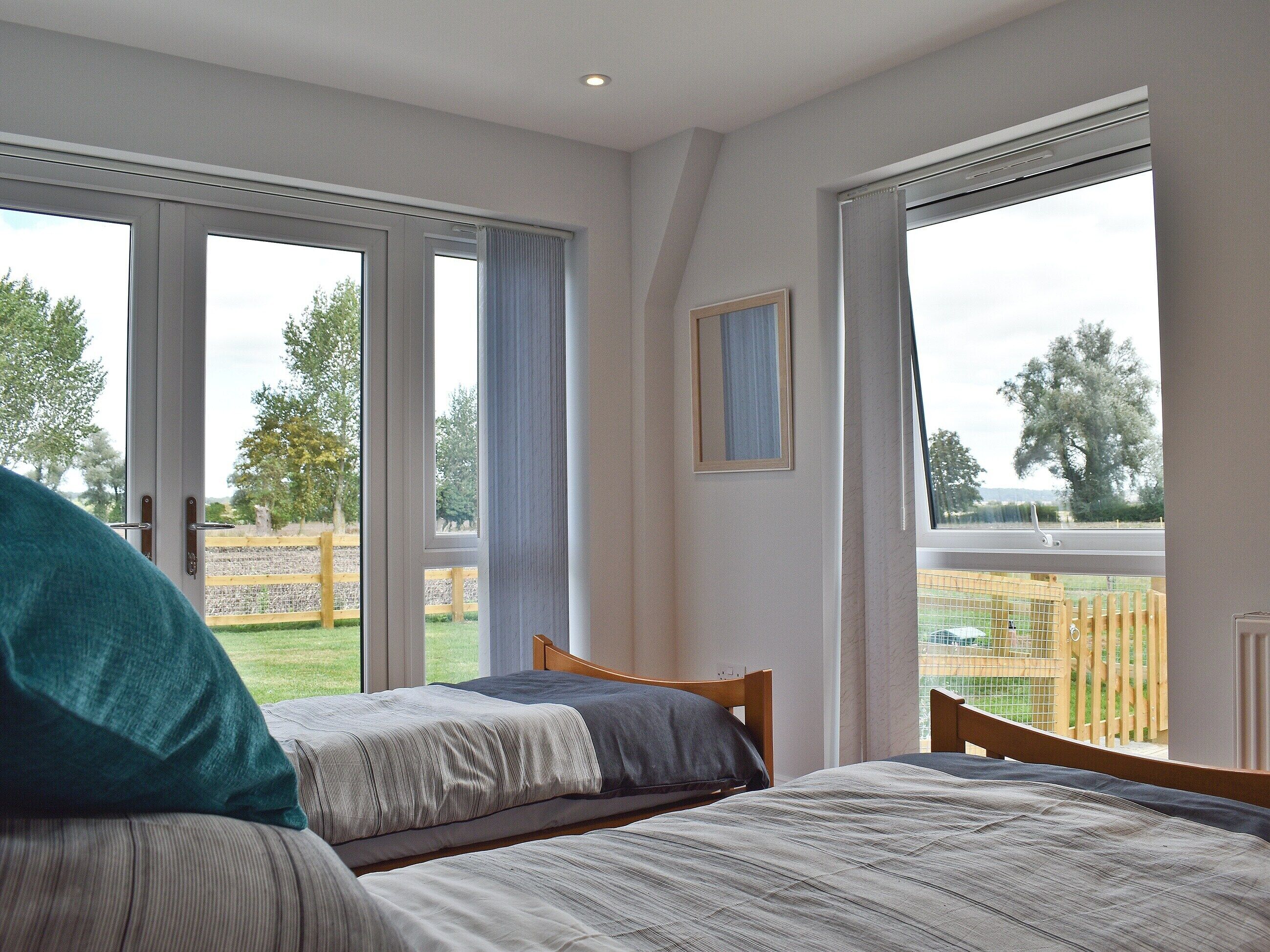 A bedroom with two beds, large windows, and a view of the outdoors.