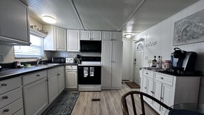 A compact kitchen with white cabinets, a microwave, a stove, and a coffee maker. - Welcome to our Beach House ! We have recently totally renovated and refreshed. (Port Orange)