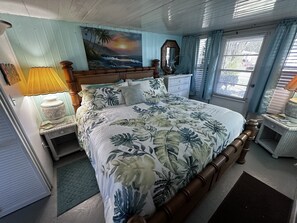 A bedroom with a bed, a nightstand, a lamp, a dresser, and a painting on the wall. - Welcome to our Beach House ! We have recently totally renovated and refreshed. (Port Orange)
