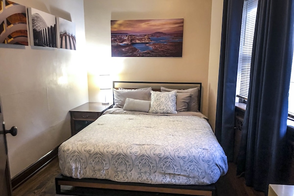 Bedroom #1 is a Queen bed, two lamps, a fan and power strip at the nightstand.