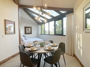A dining area with a table set for four, a bed in the background, and a skylight above. - Silver King Hotel - Walk to Ski (Park City)