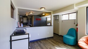 A compact living space with a kitchenette, a blue chair, and a small sofa.