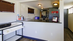 A modern kitchen with a countertop, a printer, and a window with blinds.