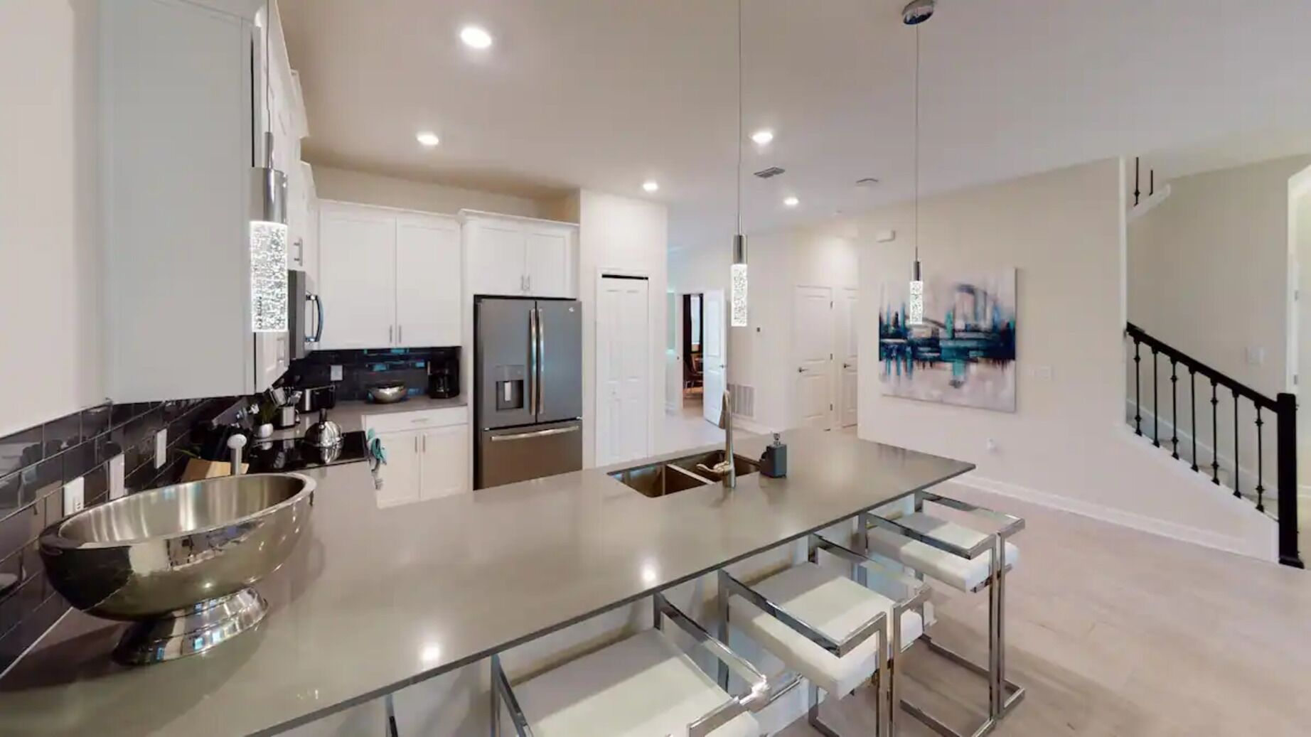 Eine moderne Küche mit Edelstahlgeräten, einer Glasinsel und einer Treppe, die zu einer zweiten Etage führt.