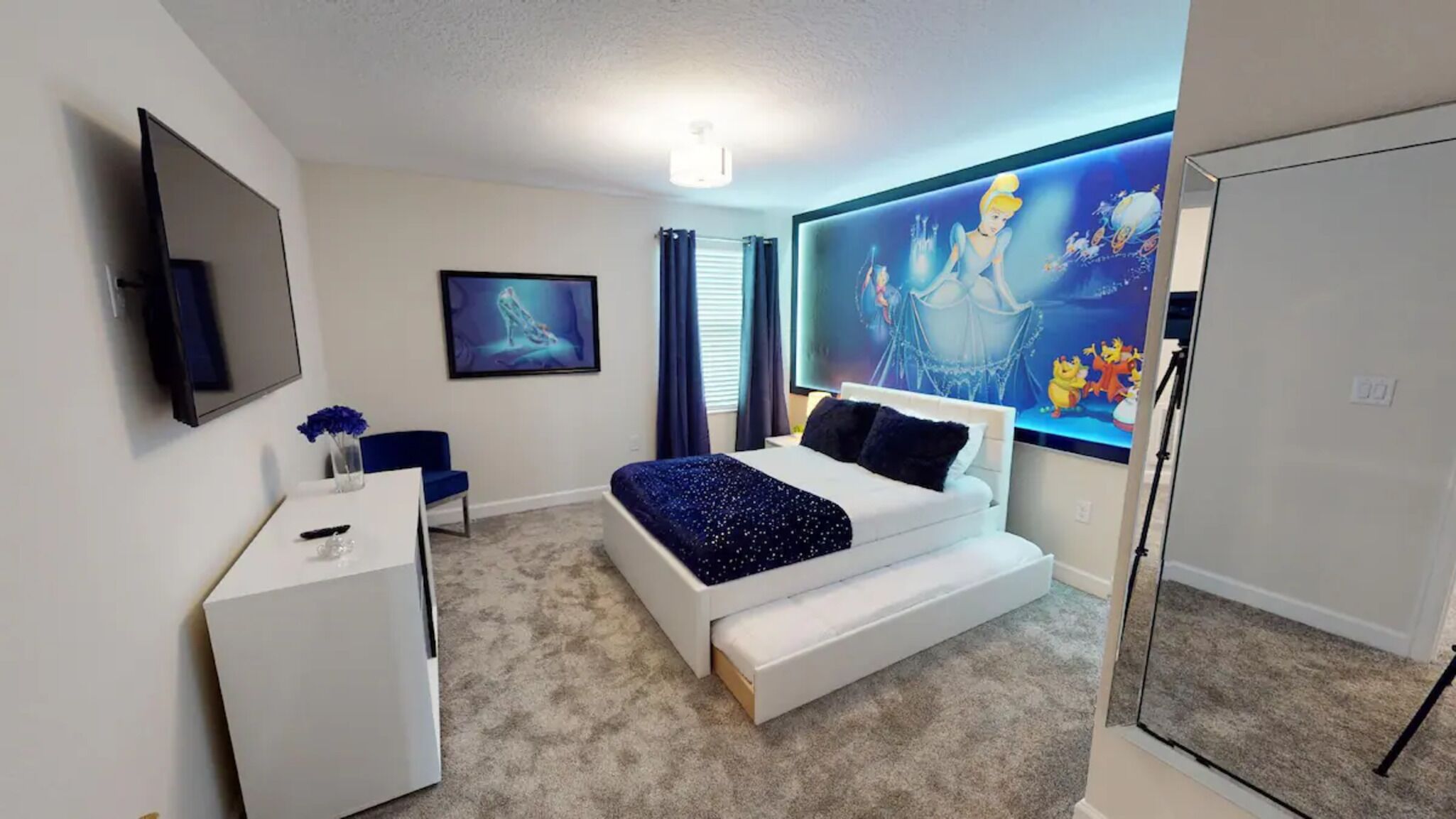 Una camera da letto moderna con un letto, una scrivania, un televisore e un'ampia finestra con un'opera d'arte.