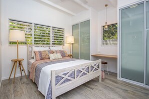 A bedroom with a bed, bedside lamps, a desk, and a view through a window. - Papillon Bleu (Horseshoe Bay)