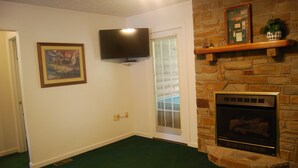 Ein Wohnzimmer mit Kamin aus Stein, einem Wand-Fernseher und einem gerahmten Bild an der Wand.
