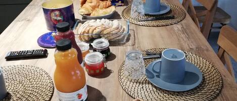 A wooden dining table set with various food items, including bread, pastries, and condiments.