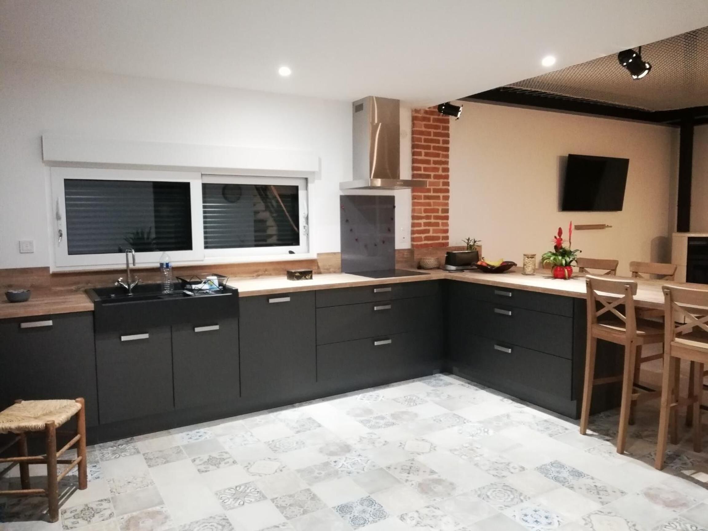 A modern kitchen with dark cabinetry, a built-in oven, and a window above the sink.