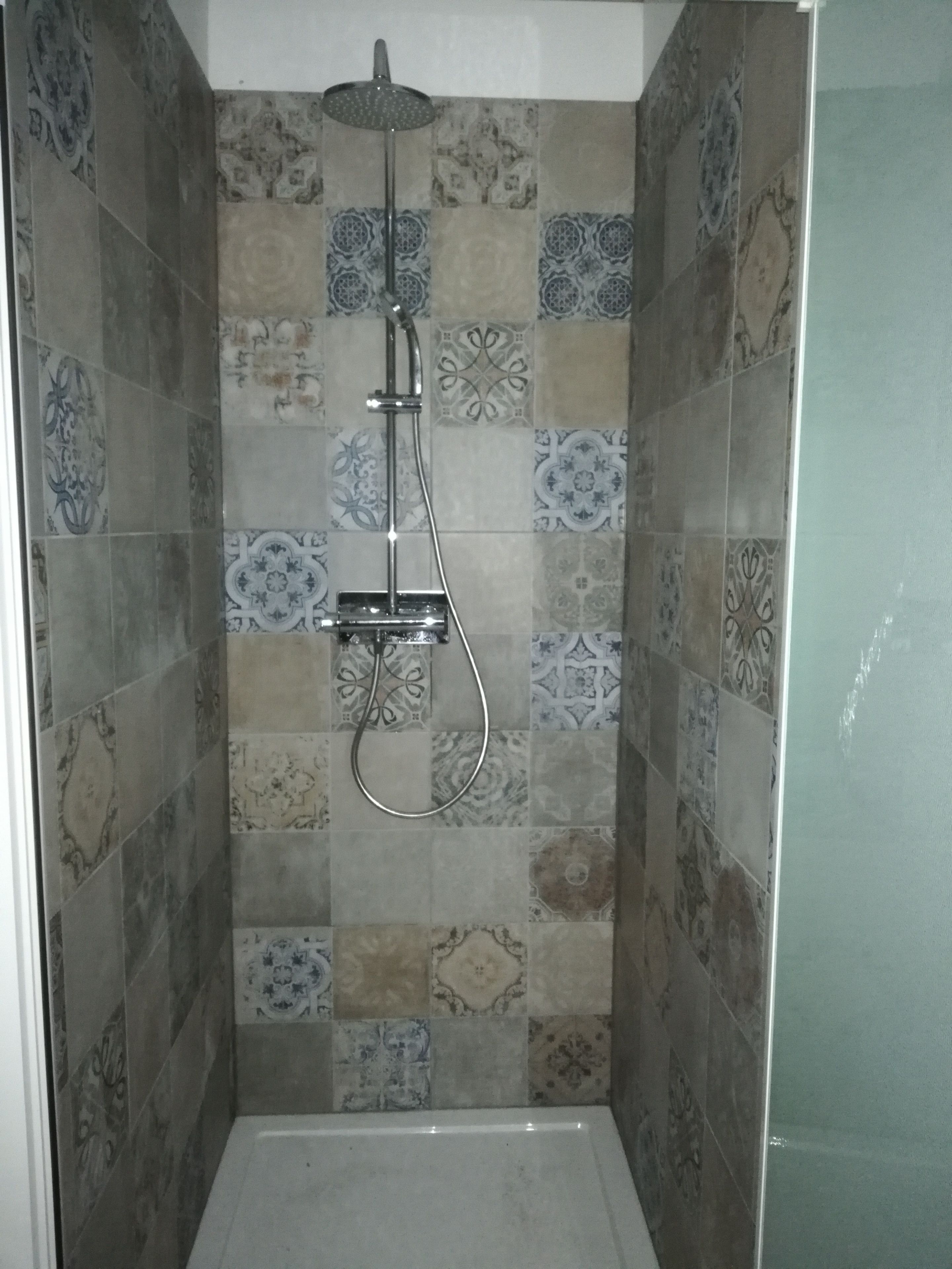 Un espace douche équipé d’un pommeau de douche à main et d’un robinet fixé au mur.