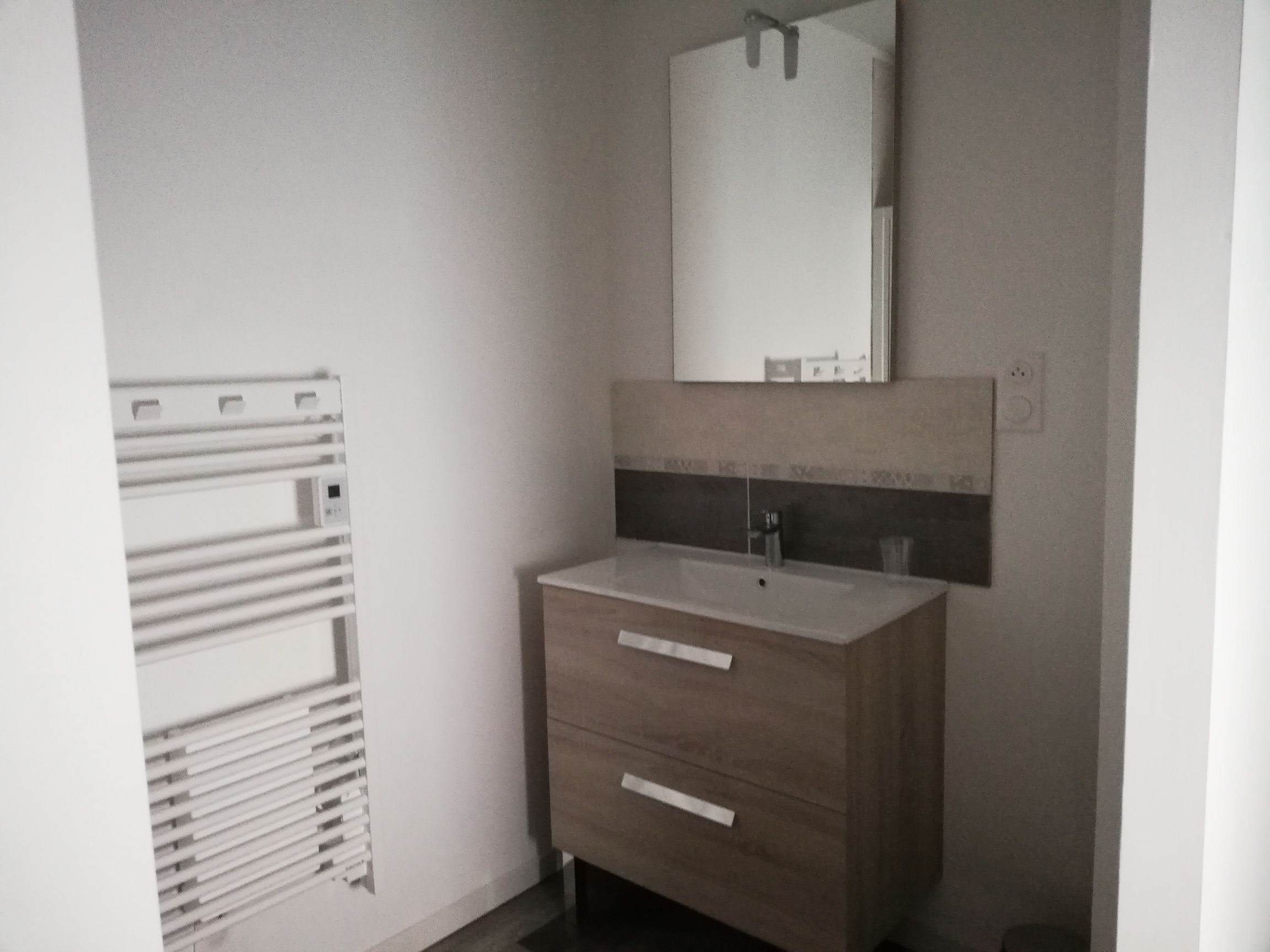 Un baño con tocador de madera, un espejo y un perchero para toallas.