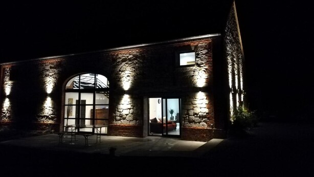 En modern byggnad med en fasad av sten, stora, välvda fönster och en väl upplyst entré.