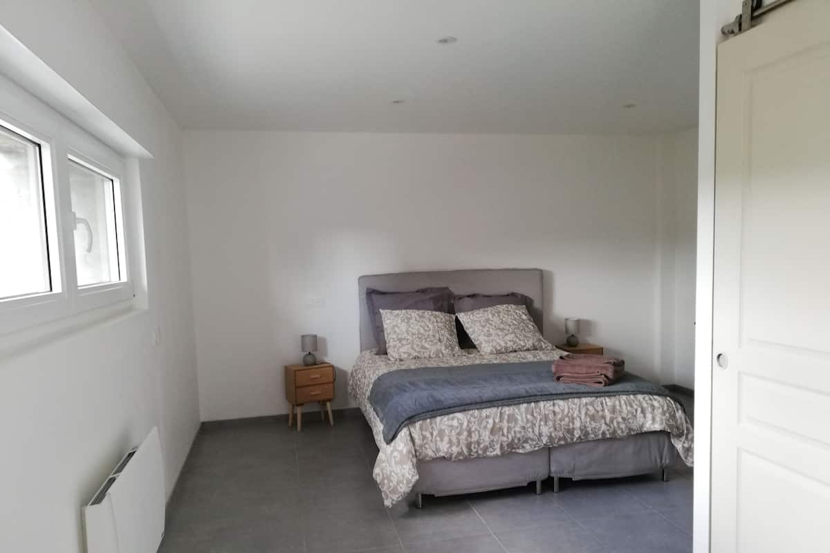 A bedroom with a bed, nightstands, and a window.