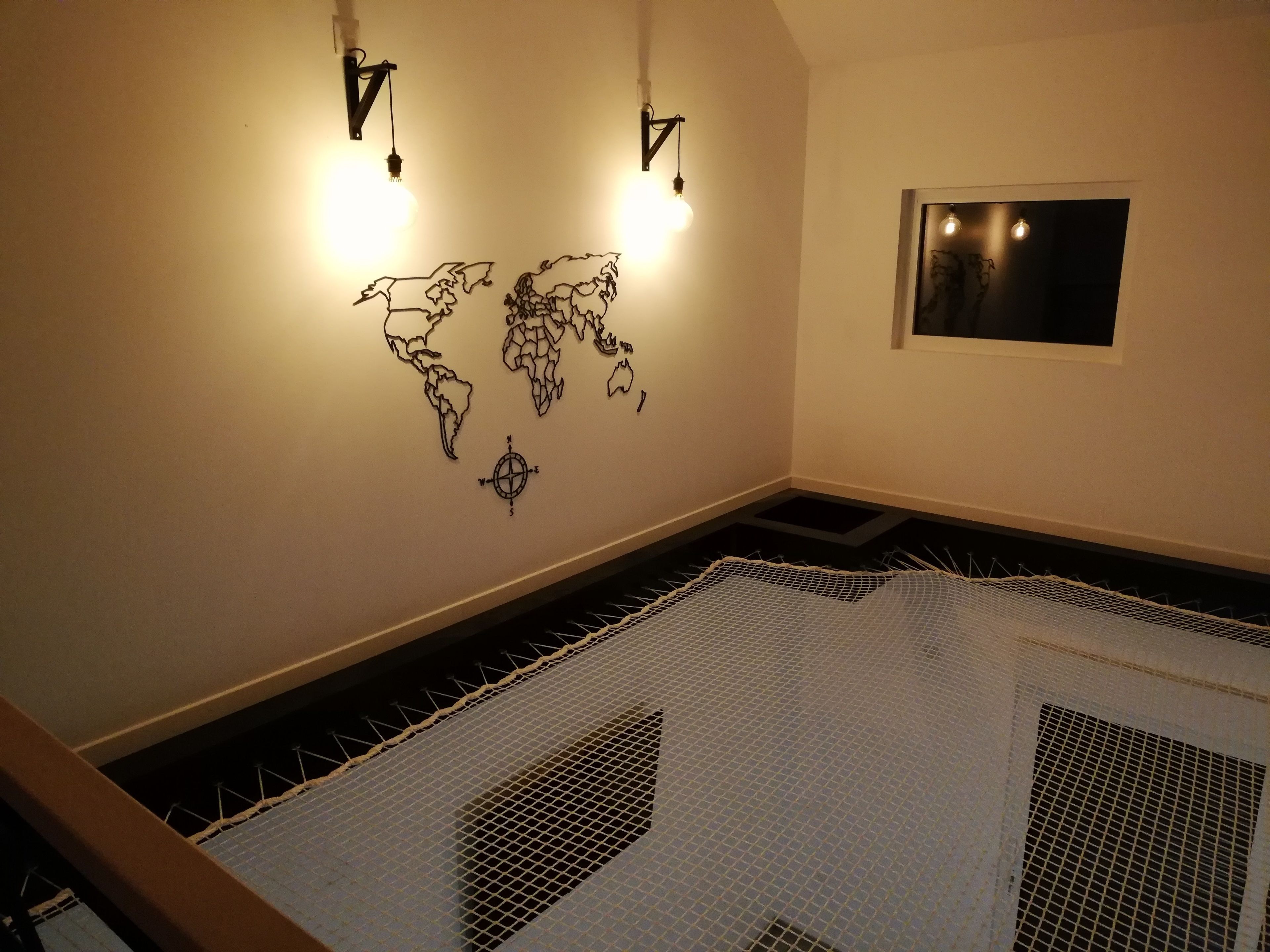 A room with a world map on the wall, two wall-mounted lights, and a framed picture.