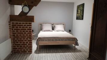 A bedroom with a wooden bed, a brick wall, and a small mirror.