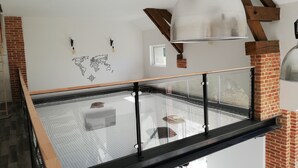 En modern loftlägenhet med ett glasgolv, synliga tegelväggar och en världskarta som dekoration.