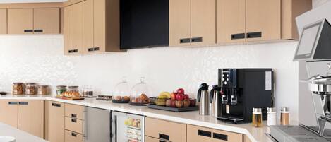 A modern kitchen with built-in appliances, a refrigerator, and a coffee machine.