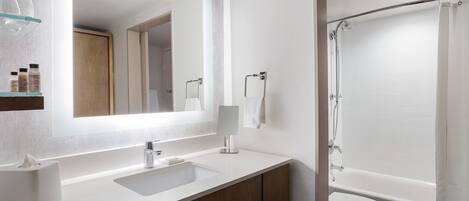 A modern bathroom with a large mirror, a sink, a toilet, and a shower.