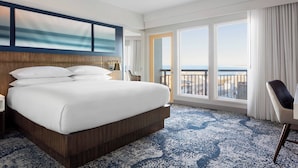 Habitación de hotel con una cama grande, vistas al mar a través de las ventanas y un balcón.