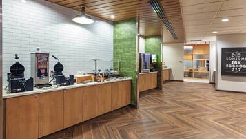 A breakfast bar with waffle makers, a coffee machine, and a menu board.