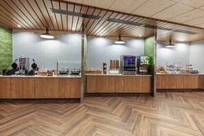 Una cocina moderna con armarios de madera, piso con patrón de espiga y lámparas colgantes.