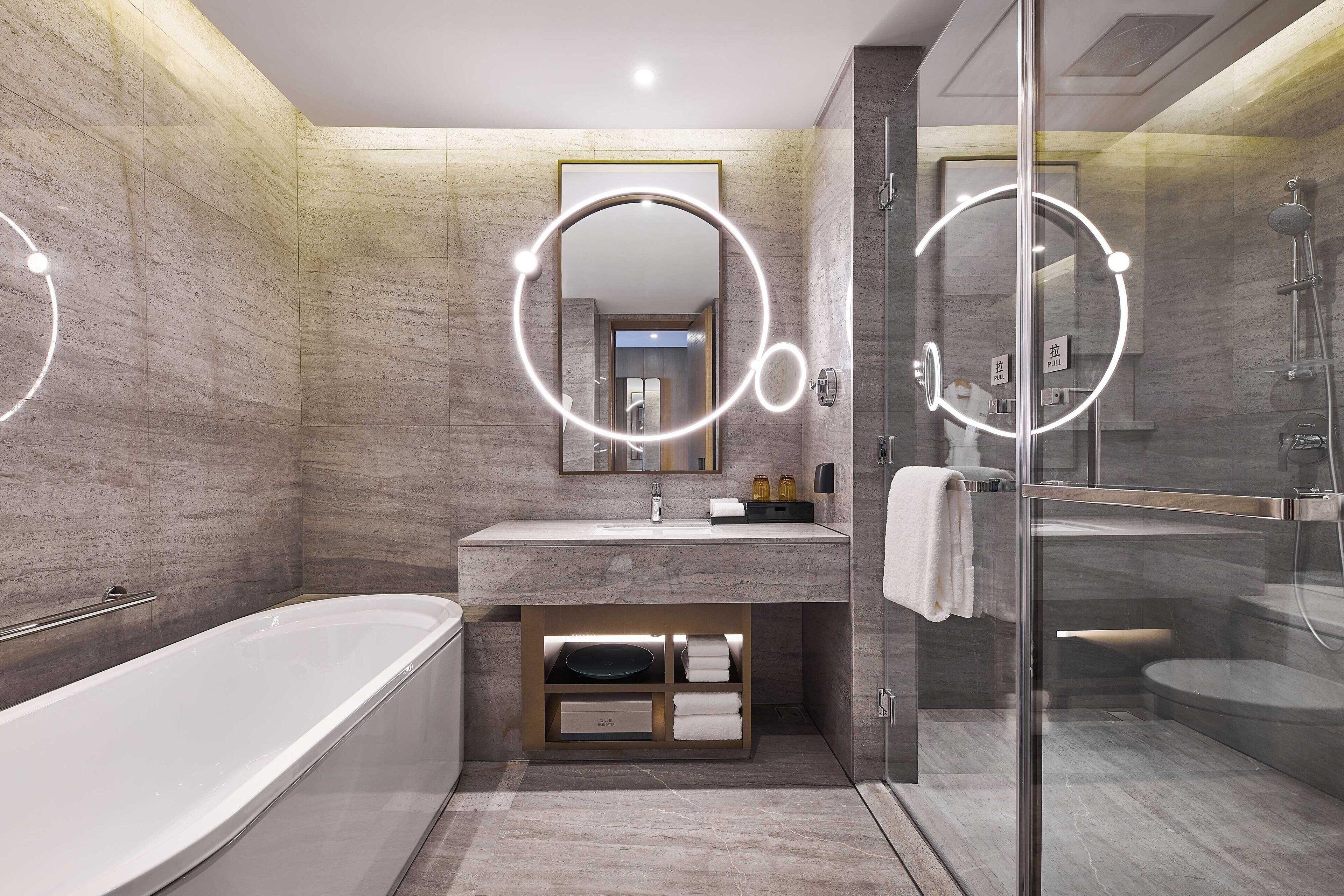 A modern bathroom with a freestanding bathtub, a glass-enclosed shower, and a vanity with a mirror.