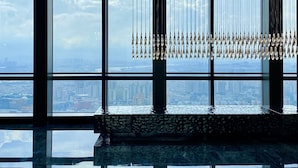 Un intérieur moderne avec de grandes fenêtres, un sol réfléchissant et un élément décoratif suspendu.