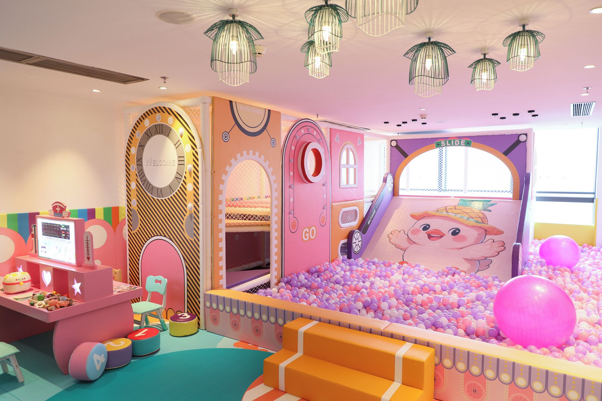A children's play area with a ball pit, a slide, and a 'Welcome' sign.
