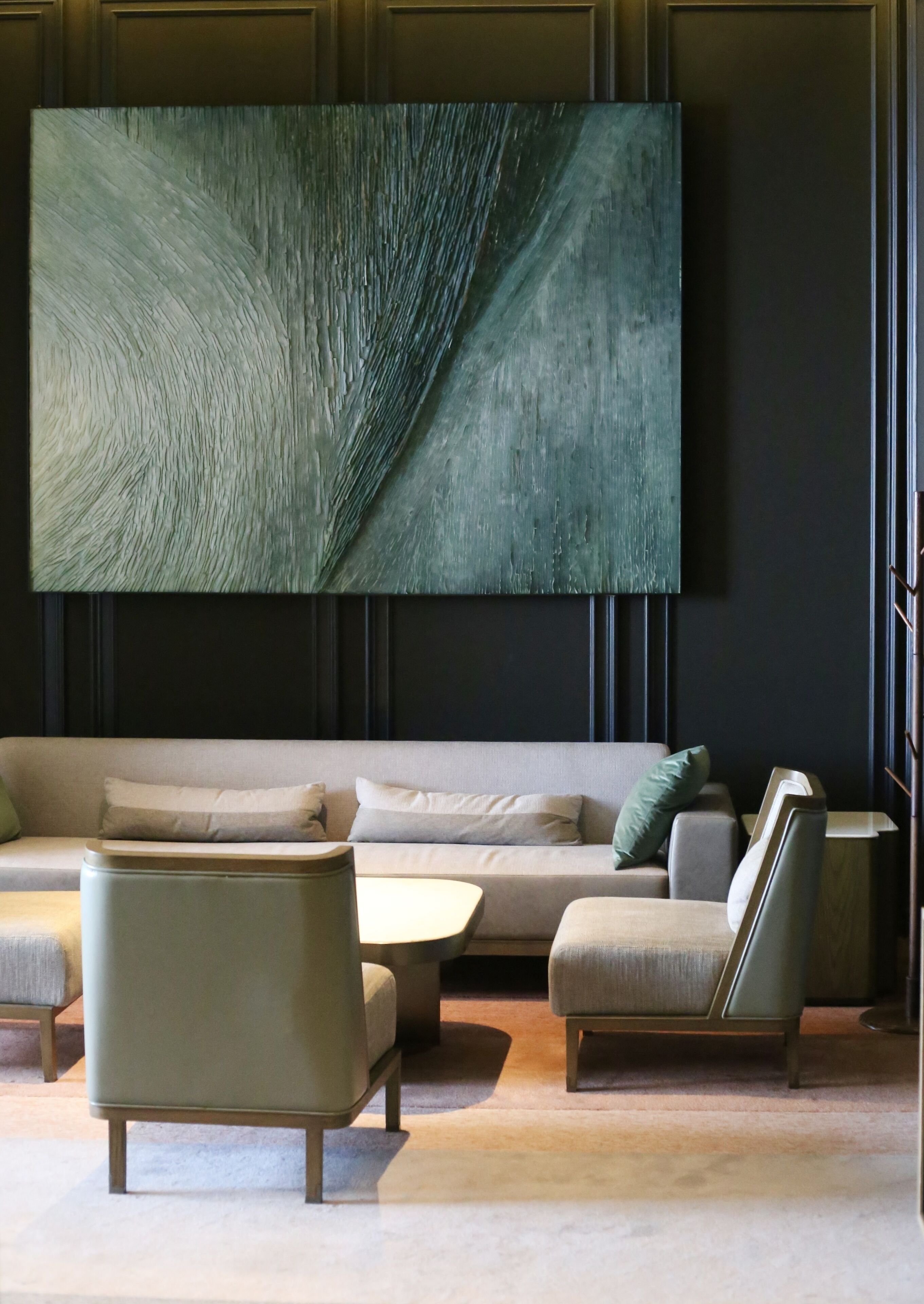 A modern living room with a large abstract painting, a sofa, two armchairs, and a coffee table.