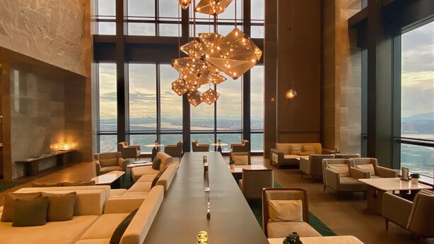Un salon spacieux avec une longue table, des sièges confortables et de grandes fenêtres offrant une vue sur la ville.
