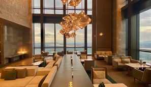 A spacious lounge with a long table, comfortable seating, and large windows offering a city view. - The Westin Zhongshan Guzhen (Zhongshan)