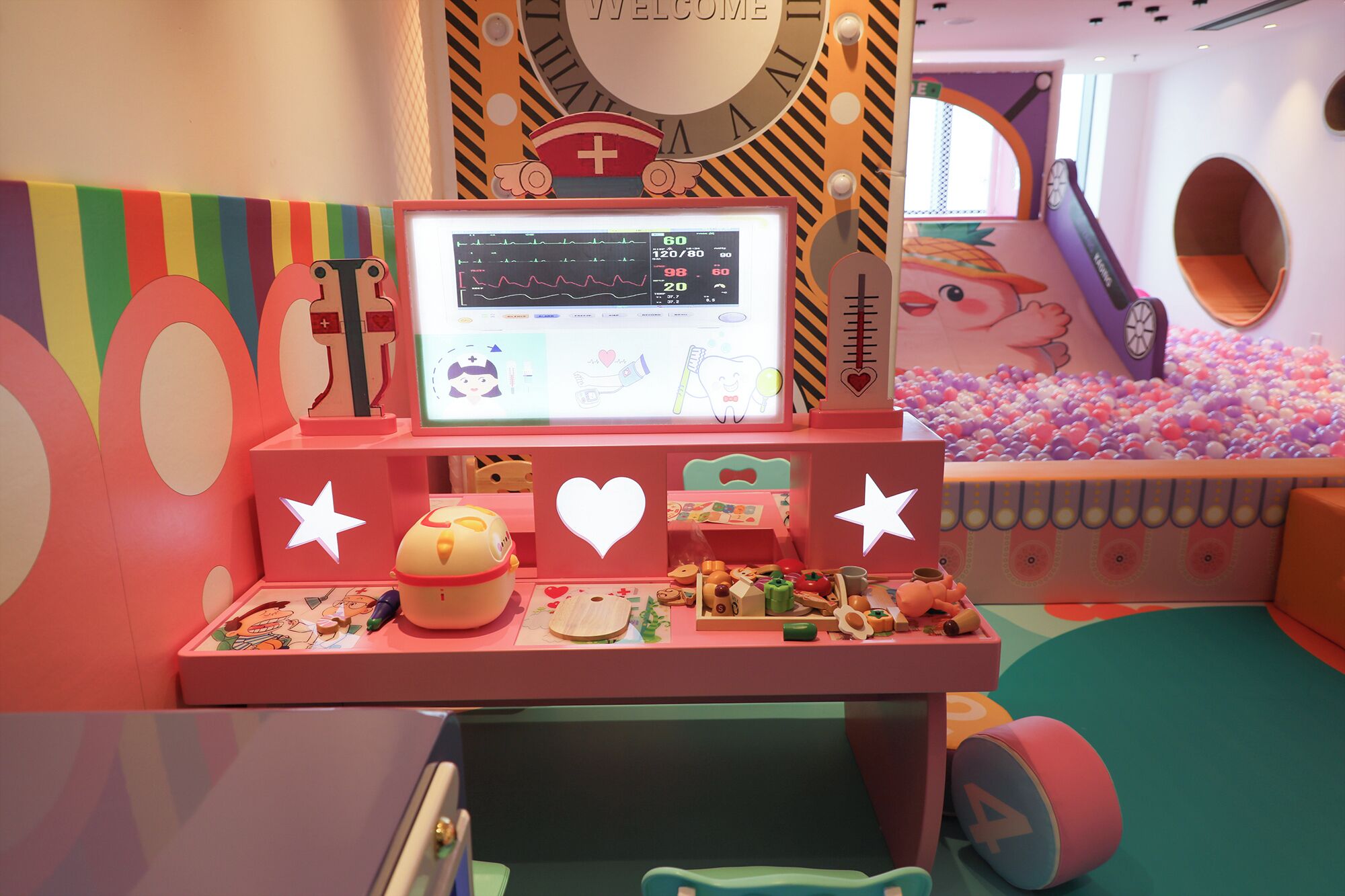 A children's play area with a computer monitor, toys, and a ball pit.