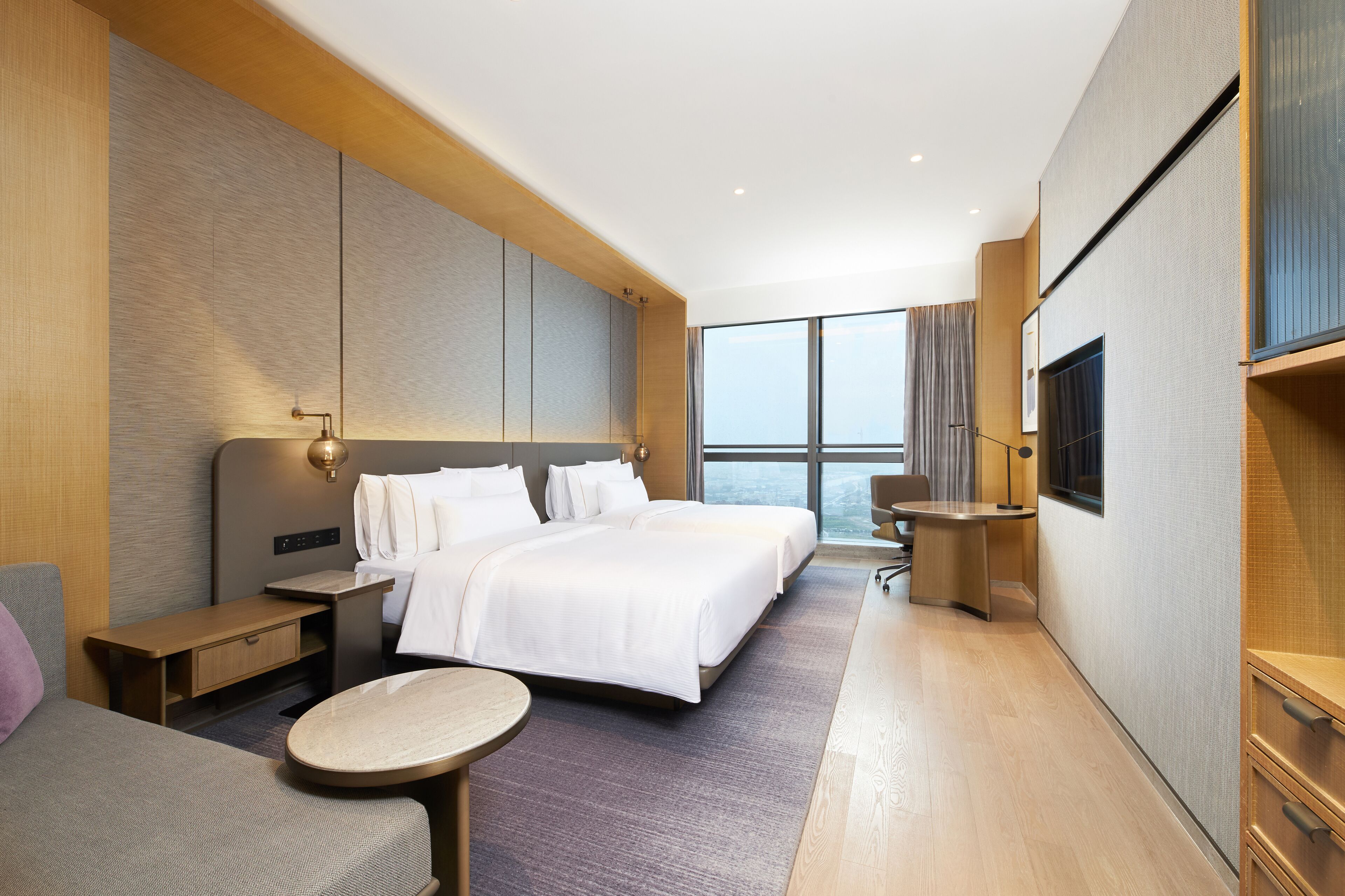 Una habitación de hotel moderna con una cama grande, un escritorio, una silla y un televisor.