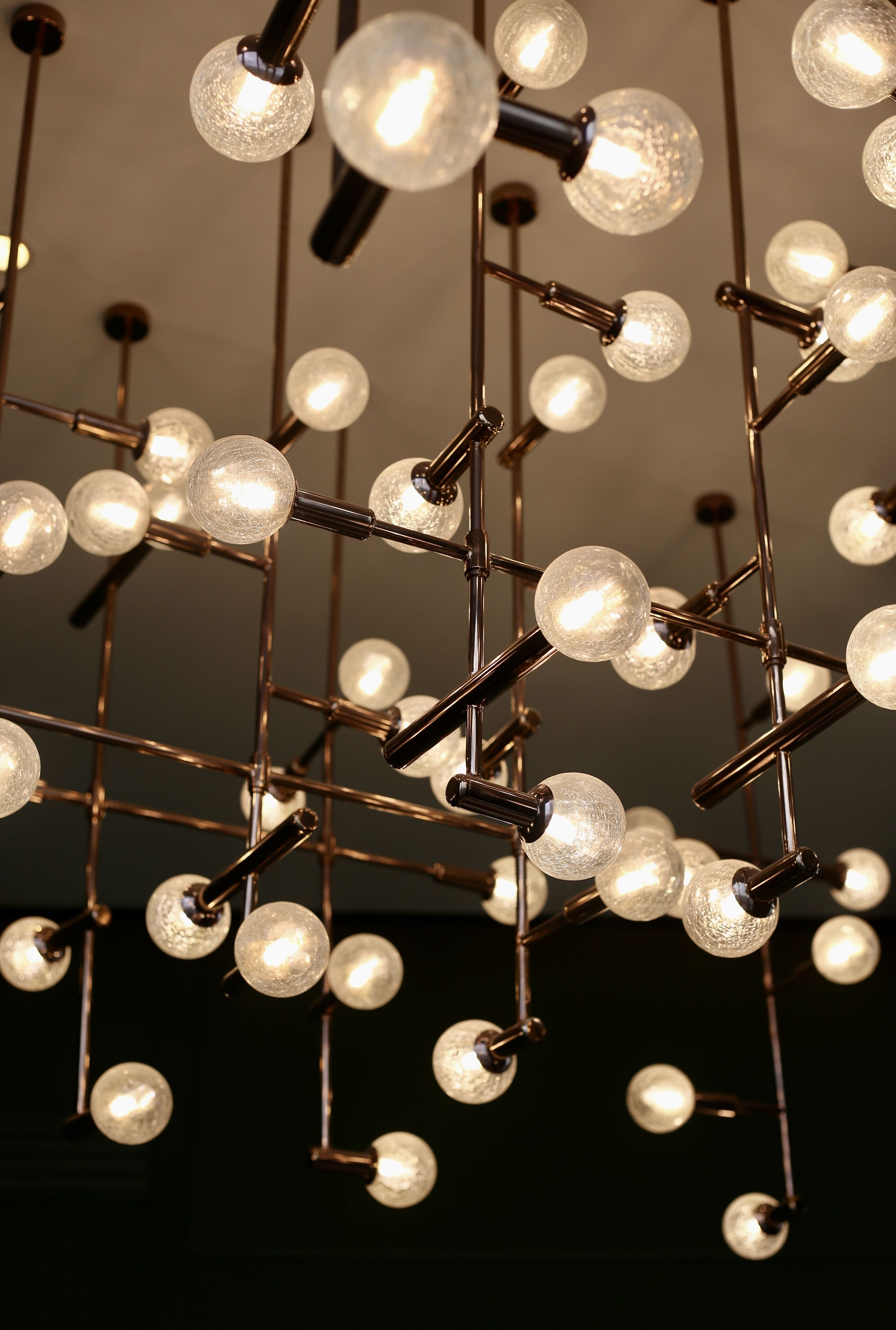A ceiling with a network of metal rods and glass globes, likely part of a lighting fixture.