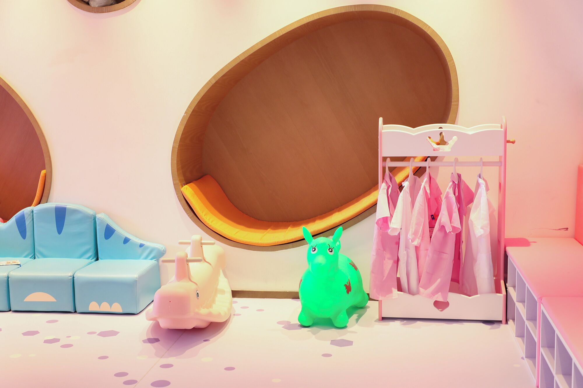 Une pièce comprenant un espace de détente circulaire, une petite table, un portant à vêtements et un éléphant en jouet.