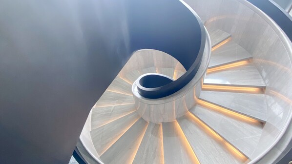 Una escalera de caracol con acabado metálico y barandillas iluminadas.